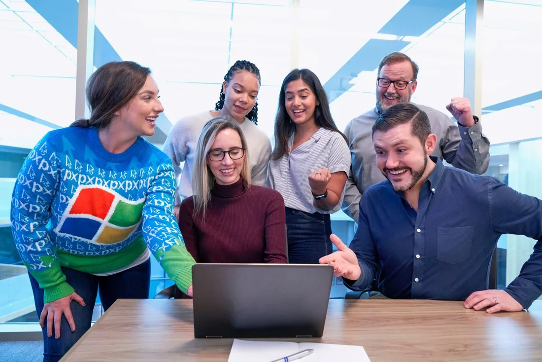 A team gathered around a laptop, reacting to a result together