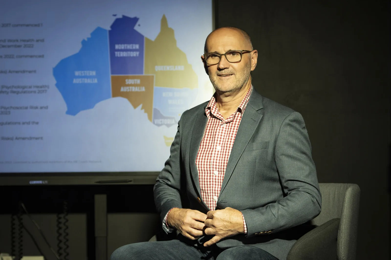 Rod Smith presenting beside a screen showing a map of Australia and a list of regulation dates