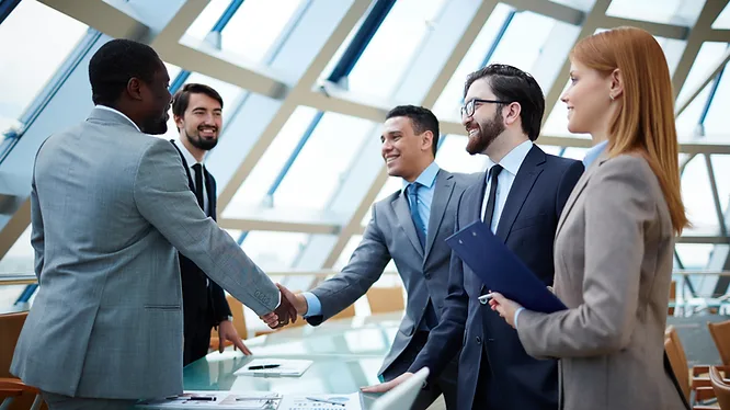 Two people shaking hands across a meeting table