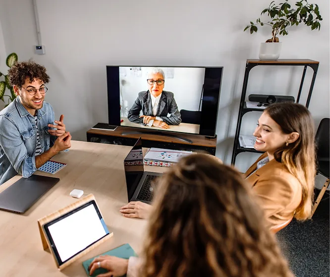 A hybrid team meeting with a colleague joining on screen